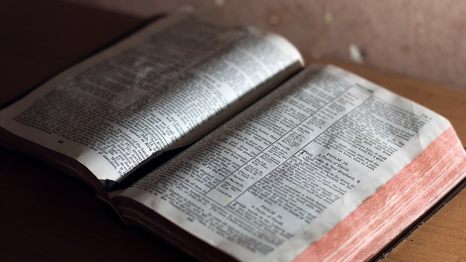 An open, worn Bible on a dark surface.