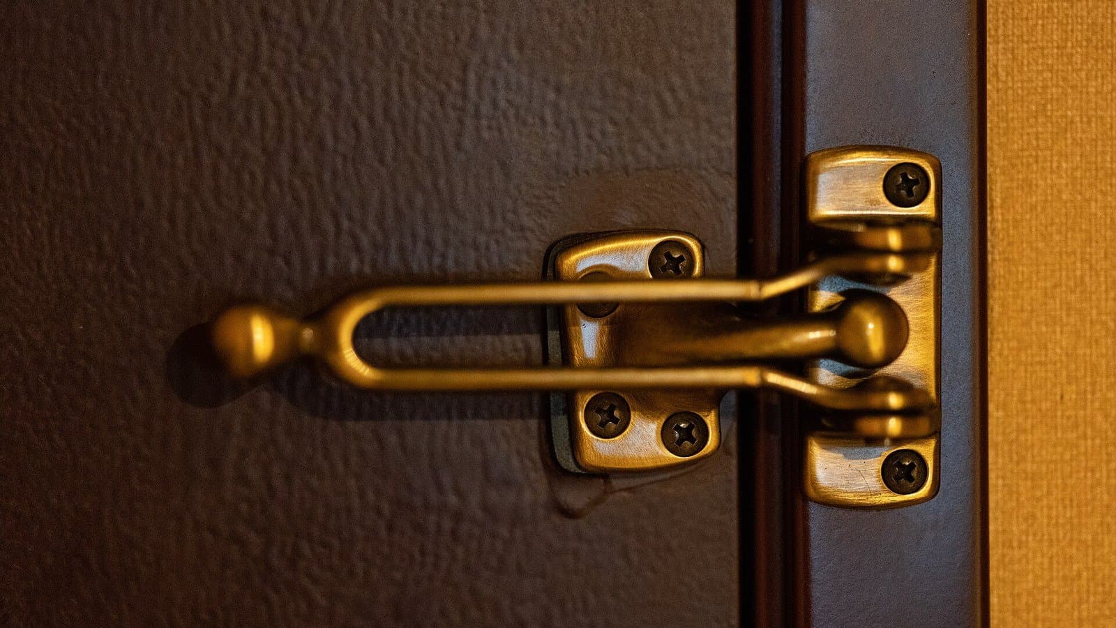 A metal security latch fastened across a closed door.
