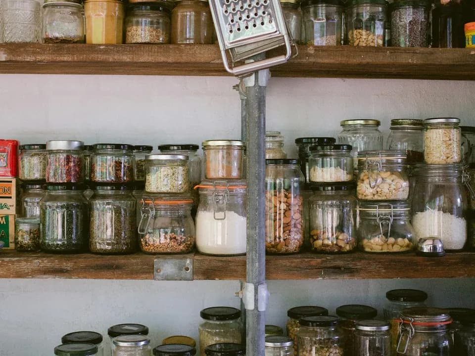 Wooden pantry shelves lined with glass jars of staple foods