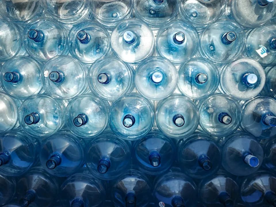 Rows of large blue water bottles stacked together for household water storage