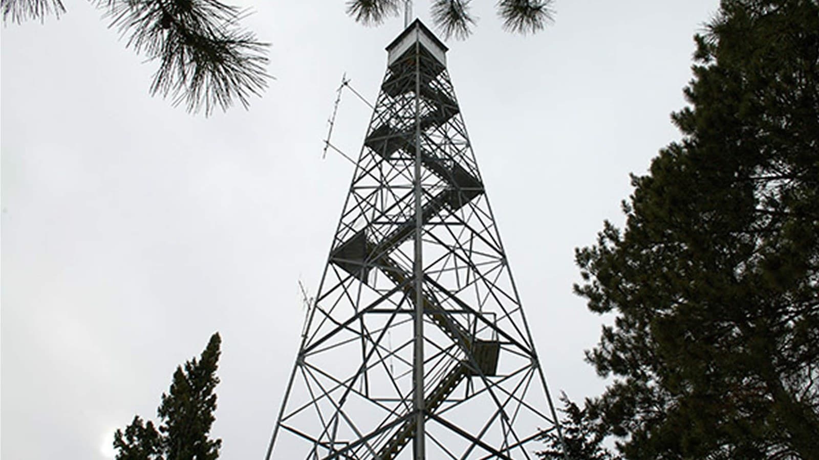 A steel fire-lookout tower viewed from below.